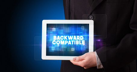 Young business person working on tablet and shows the inscription: BACKWARD COMPATIBLE