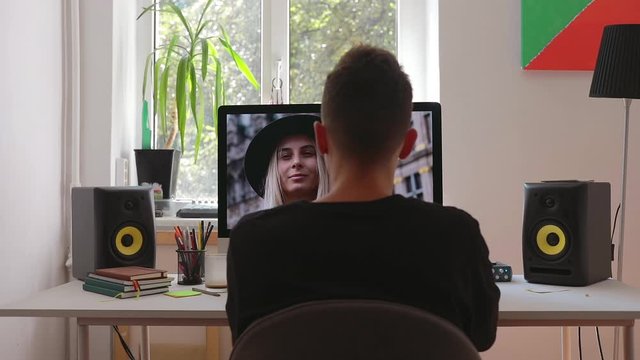 Male digital editor works in picture editing software on his personal computer with big display. He works with photo in loft room at home freelance