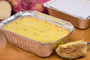 Packed lunch of diet version of shepherd's pie made of sweet potato and stuffed with ground beef in wood background