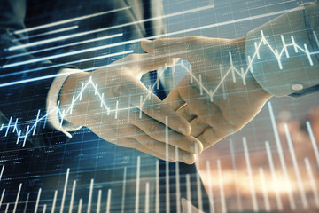 Double exposure of financial chart on cityscape background with two businessmen handshake. Concept of financial analysis and investment opportunities