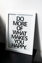 The motivational words Do more of what makes you happy on photo frame near the white wall