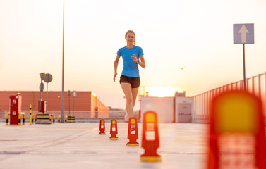 Young woman running on parking level in the city at sunset