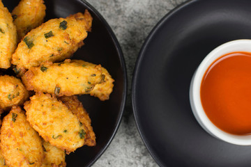 Fried rice balls called bolinho de arroz and pepper sauce in black plates in rustic background seen from above close