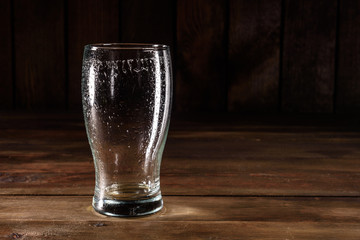 Glass of light beer on a dark pub. Glass beer on wood background with copy space. Full glass with lager beer, close up