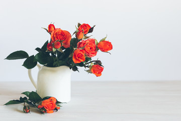 Romantic bouquet  of bright red orange roses in a jar on a white background.