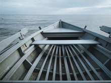 An old flat-bottomed light gray boat stands on the seashore. The concept of calm, mooring and good weather. Inside view.
