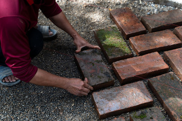 Worker laying red brick on floor. Road Paving, construction..