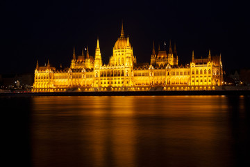 Fototapeta na wymiar The Hungarian Parliament Building, a notable landmark of Hungary in Budapest. View of the main facade illuminated above the Danube river. Long exposure at a night.