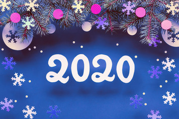 New Yerar 2020 background with fir twigs and paper decorations. Flat lay, top view on dark blue paper