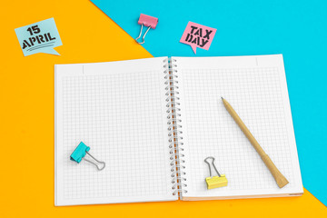 Open notebook with pencil and clip on colored background