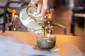 Hot green tea poured out of the teapot into the ice chocolate.