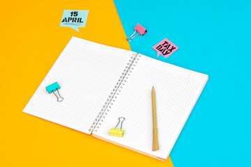 Open notebook with pencil and clip on colored background