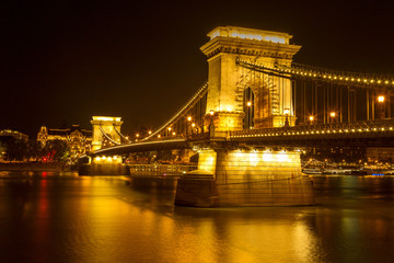 The famous Chain Bridge in Budapest, Hungary, illuminated above the Danube river. Long exposure with light trails of cars at a night.