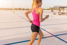 Young woman running on parking level in the city at sunset