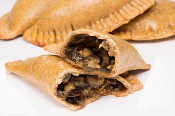 Two cut wholemeal baked pastry called pastel stuffed with eggplant om white background