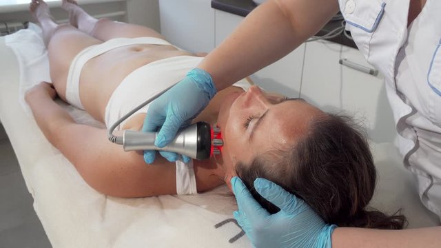 Professional beautician doing rf-lifting on her female client. Mature woman relaxing at beauty salon, getting skin tightening facial treatment. Anti-aging, wrinkles concept