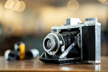 Naklejka na ściany i meble Retro film photo camera isolated on blurred background at light bokeh..