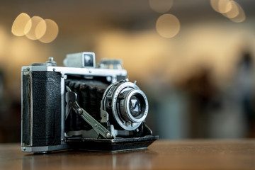 Retro film photo camera isolated on blurred background at light bokeh..