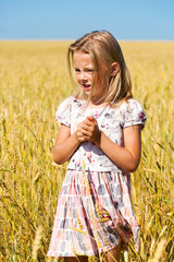 Little girl in a wheat golden field