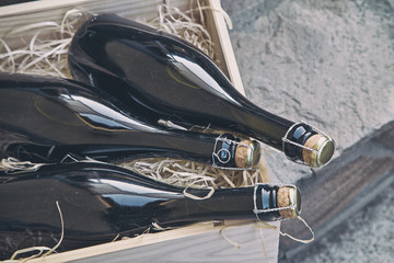 three champagne bottles in a wooden box on a stone wall background