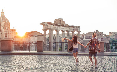 Young couple tourist walking pointing towards Roman Forum at sunrise. Historical imperial Foro...