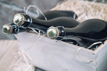 three champagne bottles in a wooden box on a stone wall background