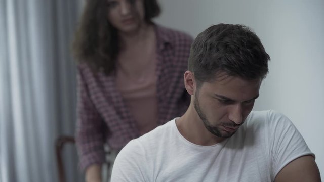 Young curly woman swearing and screaming to her curly annoying boyfriend in the living room becouse of misunderstanding.