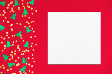 Empty white square flyer or business card mockup with soft shadows on red background with metallic foil christmas trees and gold stars confetti. Flat lay, top view. Simple holiday concept.