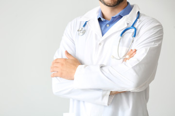 Male doctor with stethoscope on light background, closeup