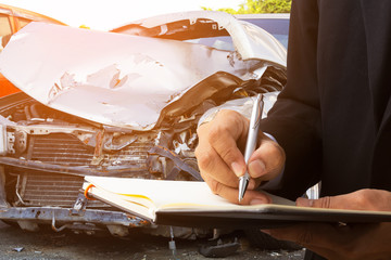 Insurance company representatives recording car accident damage in order to claim insurance.