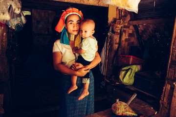 Long Neck Woman is sitting with her child. Tribal village Northern Thailand.