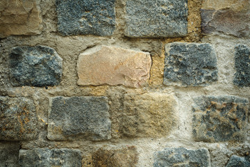 art background of an old wall with a masonry of multi-colored rectangular granite blocks and cement mortar. close-up
