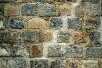 art background of an old wall with a masonry of multi-colored rectangular granite blocks and cement mortar. side view