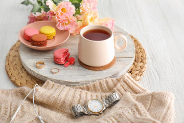 Cup of hot tea, flowers and macarons on table