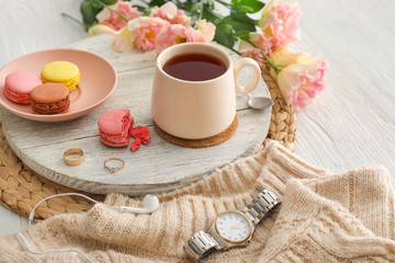 Obraz na płótnie Canvas Cup of hot tea, flowers and macarons on table