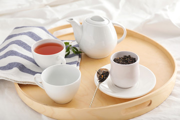 Tray with hot tea on bed in morning