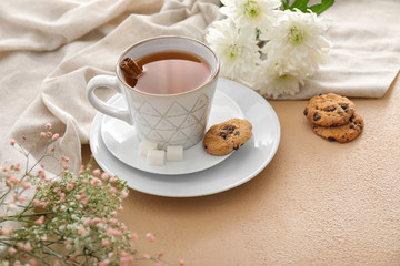 Cup of hot tea, cookies and flowers on table