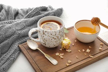 Cup of hot tea with lemon, honey and flower on table