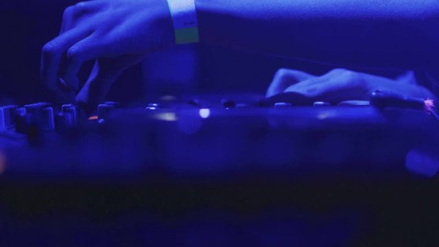 4k Close up of DJ desk pult. DJ are playing during disco party laser light show music festival. DJ hands on mixer controlling. Shooted on Red Epic Dragon camera. Slow motion DJ footage. Cinematic View
