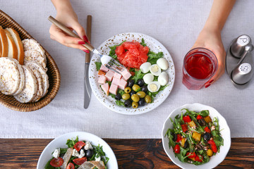 Woman eating fresh salad at table, top view