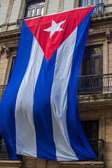 A large Cuban flag draped over balconies in Havana, Cuba