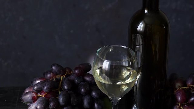 Black grapes, a glass of white wine and a bottle of wine on dark table Video HD