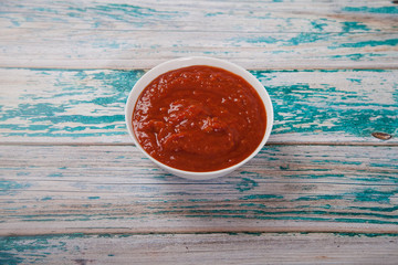 Harissa in a cup on a blue wooden background. Flat lay. Iop view.