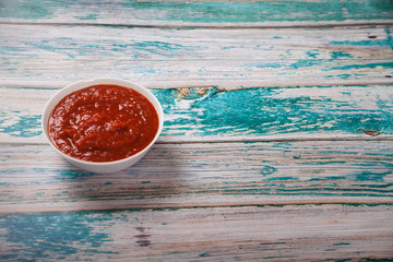 Harissa in a cup on a blue wooden background. Flat lay. Iop view. Horizontal.