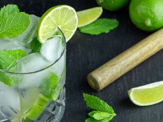 A mojito cocktail made from fresh mint and lime in a cut glass tumbler against a black slate...