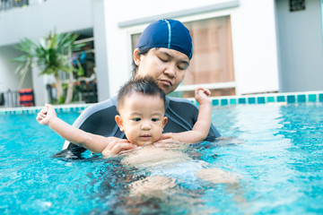 Toddler baby boy enjoying swimming with mom in pool