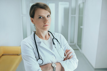 Middle aged female doctor standing in hospital corridor with stethoscope