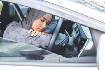 Muslim women sleep in car on steering wheel.