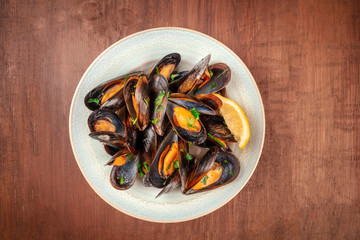 Marinara mussels, moules mariniere, overhead shot on a dark rustic wooden background