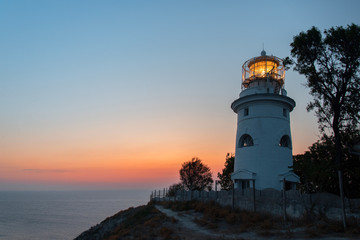White sea lighthouse in Feodosia, Crimea on the Black Sea from the light under the evening sky